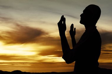 Müslüman adamın silueti dua ediyor.