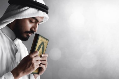Kutsal Kuran 'ı tutan dindar Arap Müslüman adam.