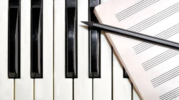 Клавиатура с нотами и карандашом — стоковое фото