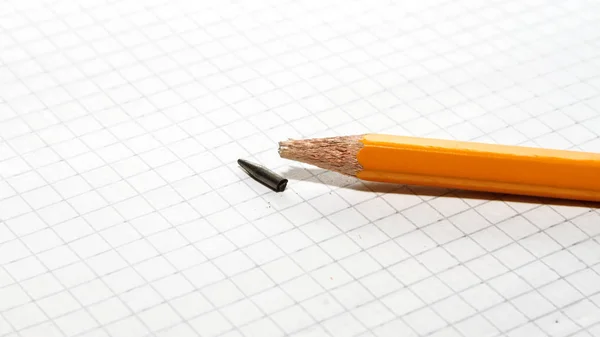 Gebrochener Bleistift auf kariertem Papier — Stockfoto