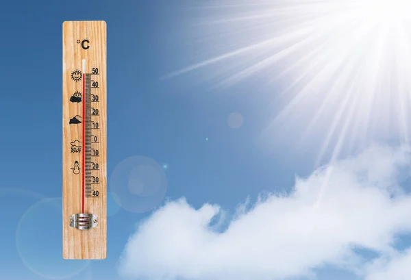 Thermometer en de zon op een blauwe hemel — Stockfoto