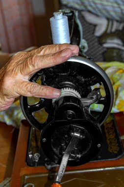 Dikiş makinesinin sapındaki kadın eli.