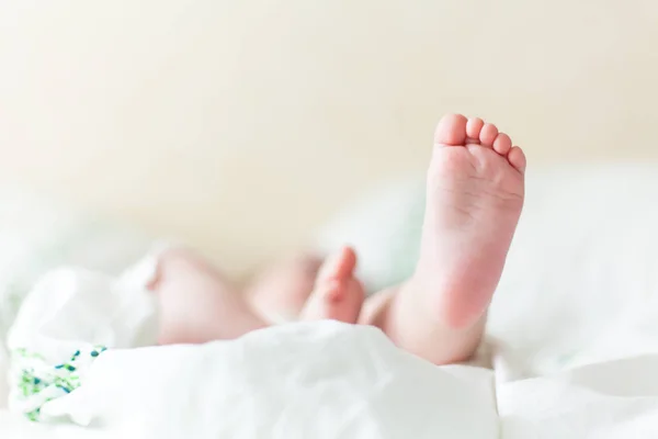 Baby fötter i vit säng — Stockfoto