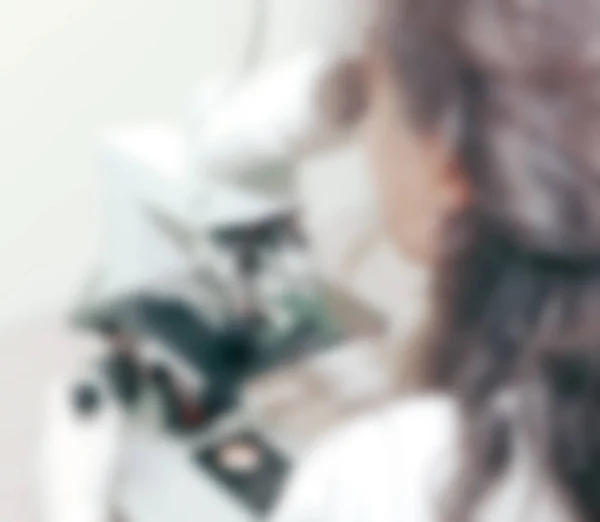 女性实验室技术员通过显微镜对样品进行分析 医学检测与临床化学和分子诊断有关 通常在医学实验室进行 — 图库照片