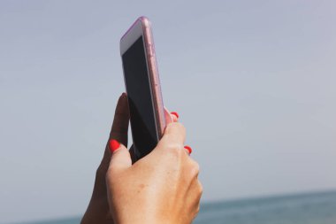 Genç bir kız sahilde selfie çekiyor.