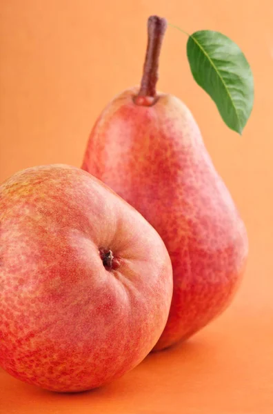 Frutti di pera rossa con foglia di pera verde su sfondo rosso — Foto Stock