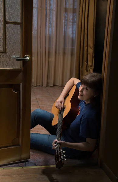 katta oturan ve gitar çalmak bir kadın