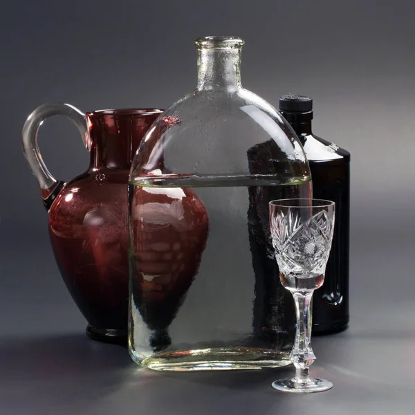 Dzban, butelkę i szkła kryształowego na szarym tle — Zdjęcie stockowe