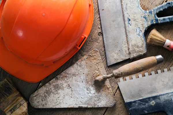 Bir kask, bir mala, fırçalar ve spatula ahşap bir masa üzerinde