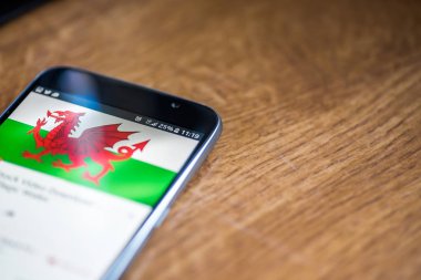 Ahşap arka plan 5g ağ işareti yüzde 25 ücret ve Galler bayrak üstünde belgili tanımlık perde ile Smartphone