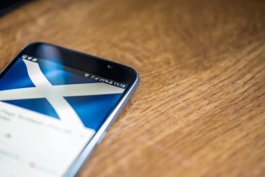 Ahşap arka plan 5g ağ işareti yüzde 25 ücret ve İskoçya bayrağı üstünde belgili tanımlık perde ile Smartphone