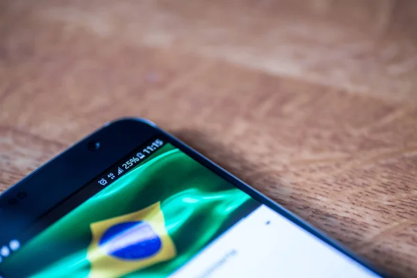 Smartphone auf Holzhintergrund mit 4g Netzwerksschild 25 Prozent Aufladung und brasilianischer Flagge auf dem Bildschirm. — Stockbild 4g-Smartphone mit 25 Prozent Aufladung und Brasilien-Flagge — Stockfoto