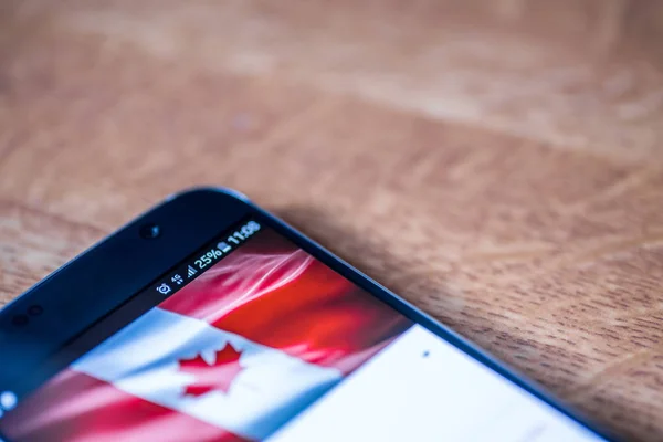 4g Smartphone με χρέωση 25 τοις εκατό και τη σημαία του Καναδά — Φωτογραφία Αρχείου