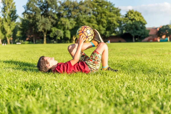 Młody chłopak piłkarz kopie piłkę na stadionie — Zdjęcie stockowe