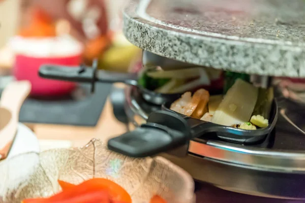 Вид на семейный стол для приготовления пищи на Raclette — стоковое фото