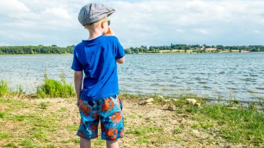 Göl arka plan üzerinde sarışın bir çocuk portresi