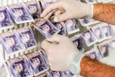 Criminal Hands In Gloves On British Sterling Pounds Notes On Clothes Dryer. Money Laundering Concept clipart