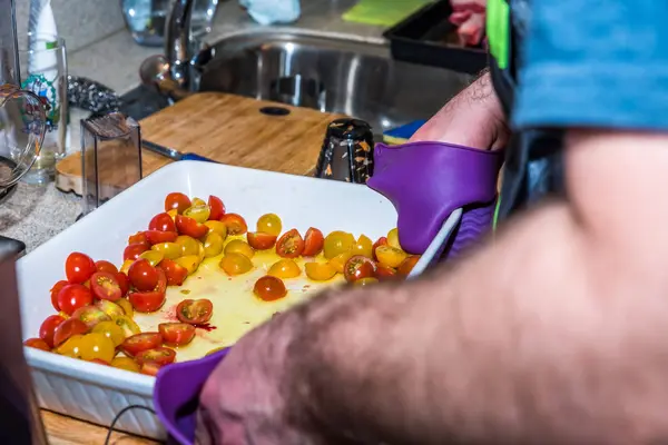 Erkek el Beyaz seramik tepsi doğranmış domates ile ham sığır eti kızartma mutfak masasının üzerinde pişirme tutarak