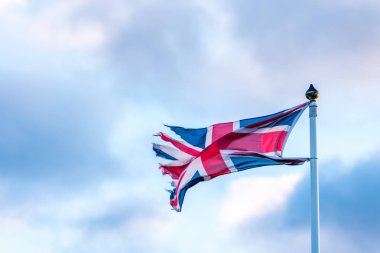 Yırtık kenarlar üzerinde bulutlu gökyüzü sallayarak ile İngiliz bayrağı