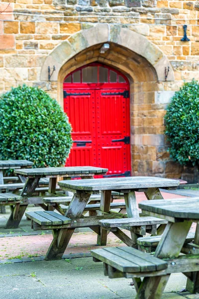 Vista giornaliera del tipico giardino pub vuoto con tavoli e porte rosse antiche in Inghilterra — Foto Stock