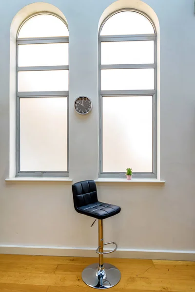 Пустой стул рядом с кактусом в цветочном горшке в ярком окне и часы на стене — стоковое фото