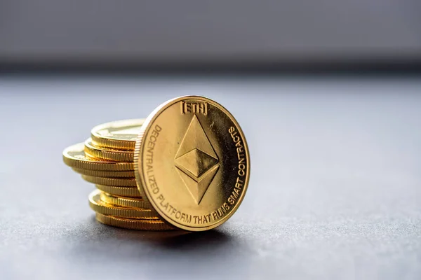 Golden virtual money Ethereum crypto currency coins stacked on a dark background