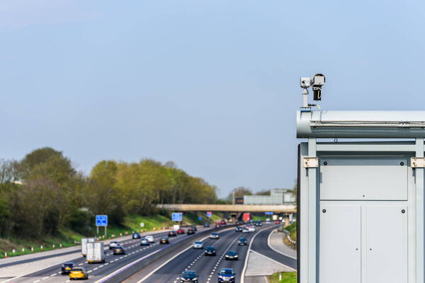 Sunny day view of UK motorway traffic with CCTV camera on foreground