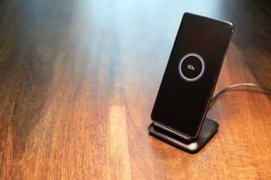 akıllı telefon kablosuz şarj standı üzerinde% 60 simge ekranda ahşap masa üzerinde