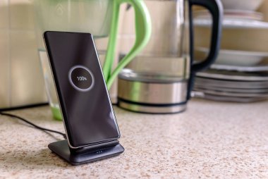akıllı telefon kablosuz şarj standında% 100 simge ile mutfak masasında