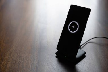 akıllı telefon kablosuz şarj standı üzerinde% 84 simge ekranda ahşap masa üzerinde