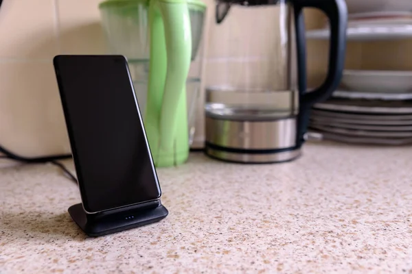 smartphone wireless charging on charging stand on kitchen tabletop