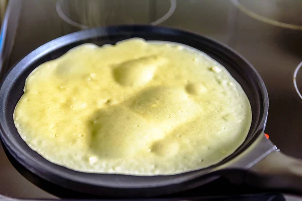 pancake frying pan with crepe pancake cooking on cooker in kitchen