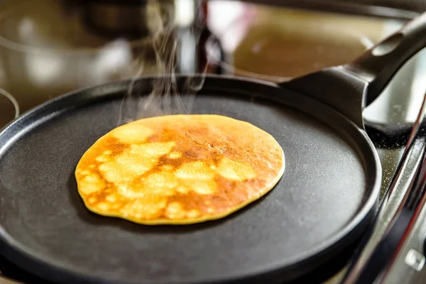 pancake frying pan with crepe pancake cooking on cooker in kitchen