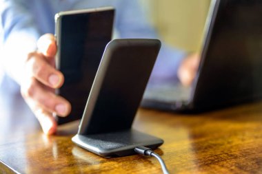 Adam akıllı telefonu kablosuz şarj cihazıyla şarj ediyor.