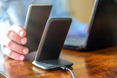 Adam akıllı telefonu kablosuz şarj cihazıyla şarj ediyor.