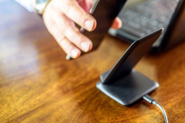 Adam akıllı telefonu kablosuz şarj cihazıyla şarj ediyor.