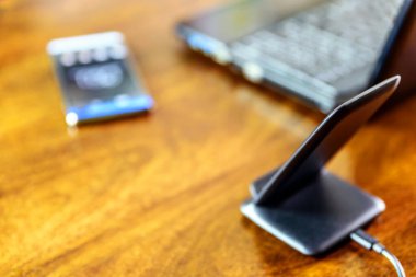 Kablosuz telefon şarjı akıllı telefon ve dizüstü bilgisayarın üzerinde duruyor.