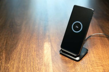 akıllı telefon kablosuz şarj standı ahşap masada ekranda% 75 simge ile
