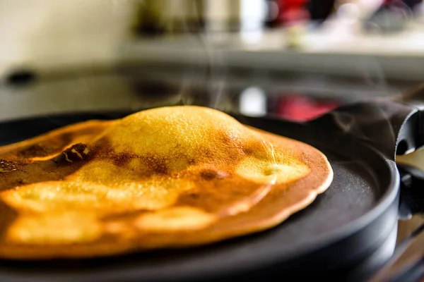 pancake frying pan with crepe pancake cooking on cooker in kitchen