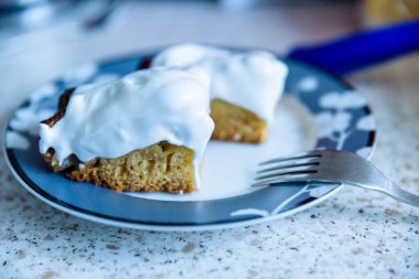 Tabakta beyaz kremayla kaplanmış taze elmalı turta parçaları servis edilmeye hazır.
