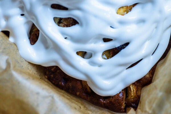 homemade fresh apple pie covered with white icing in baking tray with baking paper in it
