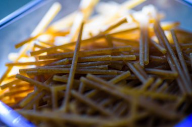 Ev mutfağındaki plastik konteynırın içindeki çiğ spagetti.