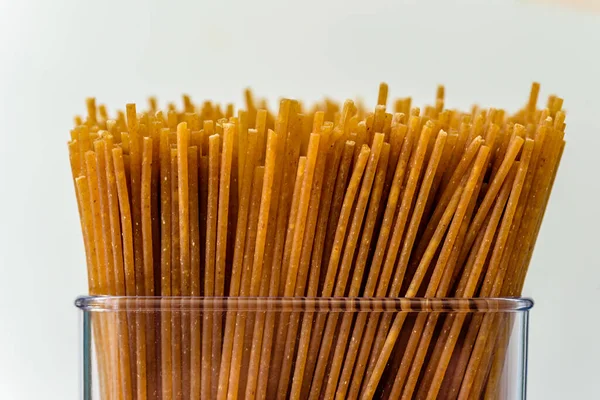 Spaghetti duri crudi all'interno di un contenitore di plastica in cucina — Foto Stock