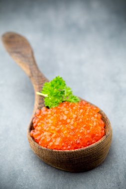Gri arka planda kaşıkla somon havyarı.