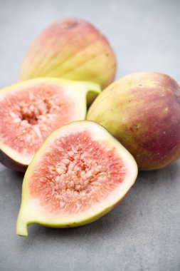 Gri bir masanın üzerinde tam bir incir ve bir incir dilimlenmiş.. 