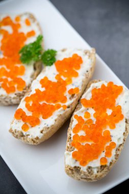 ekmek arası beyaz plaka üzerinde kırmızı havyar.