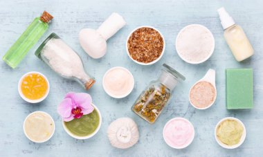 Spa aromaterapi arka planı, basit orkide çiçekleriyle süslenmiş çeşitli güzellik ürünleri..