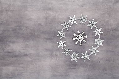 Noel kompozisyonu. Beyaz kar taneleri gri arka plandaki çelenkleri süslüyor. Noel, kış, yeni yıl konsepti. Düz konum, üst görünüm, kopyala.