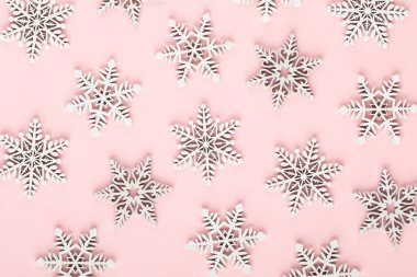 Noel arkaplanı. Pembe arka planda beyaz kar dekorasyonları.