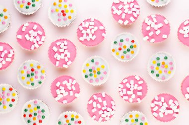 Beyaz arka planda çok renkli, güzel dekore edilmiş muffinler..